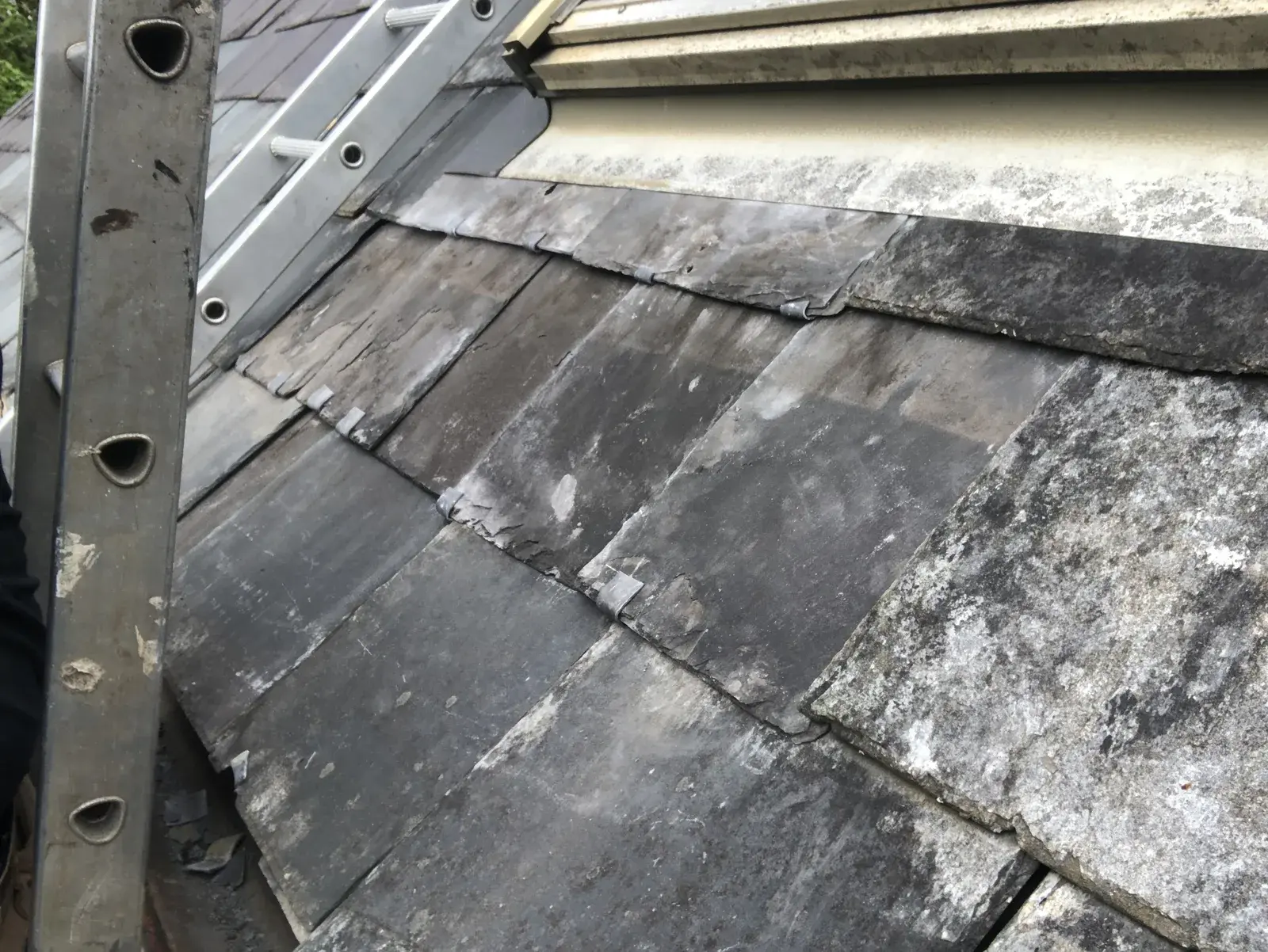 Matching Welsh slates fitted around retained roof-window flashing after storm damage