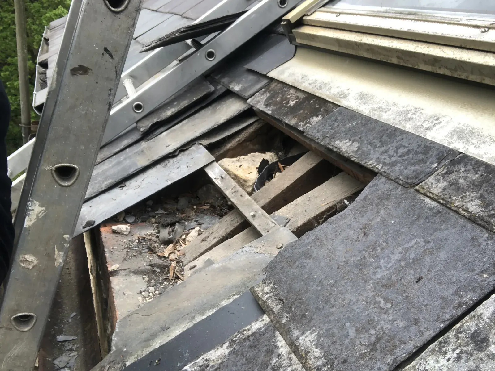 Large opening in a Welsh slate roof below a roof window after storm damage