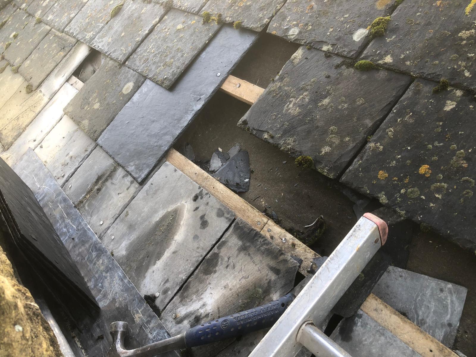 Slate covering opened beside a chimney during flashing repair work
