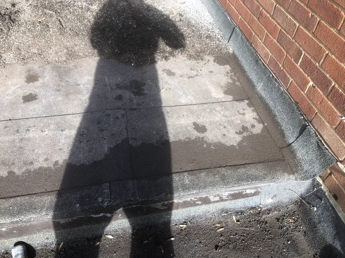 Existing felt laps and perimeter detail assessed before a temporary flat-roof repair
