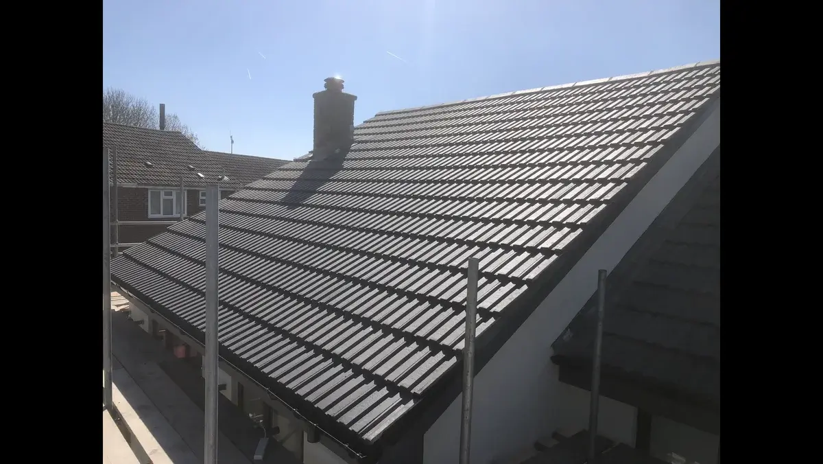 Completed full re-roof with black interlocking tiles viewed from the main slope