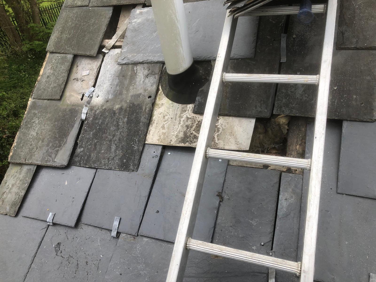 Slate covering being reinstated over repaired battens and underlay around a boiler flue