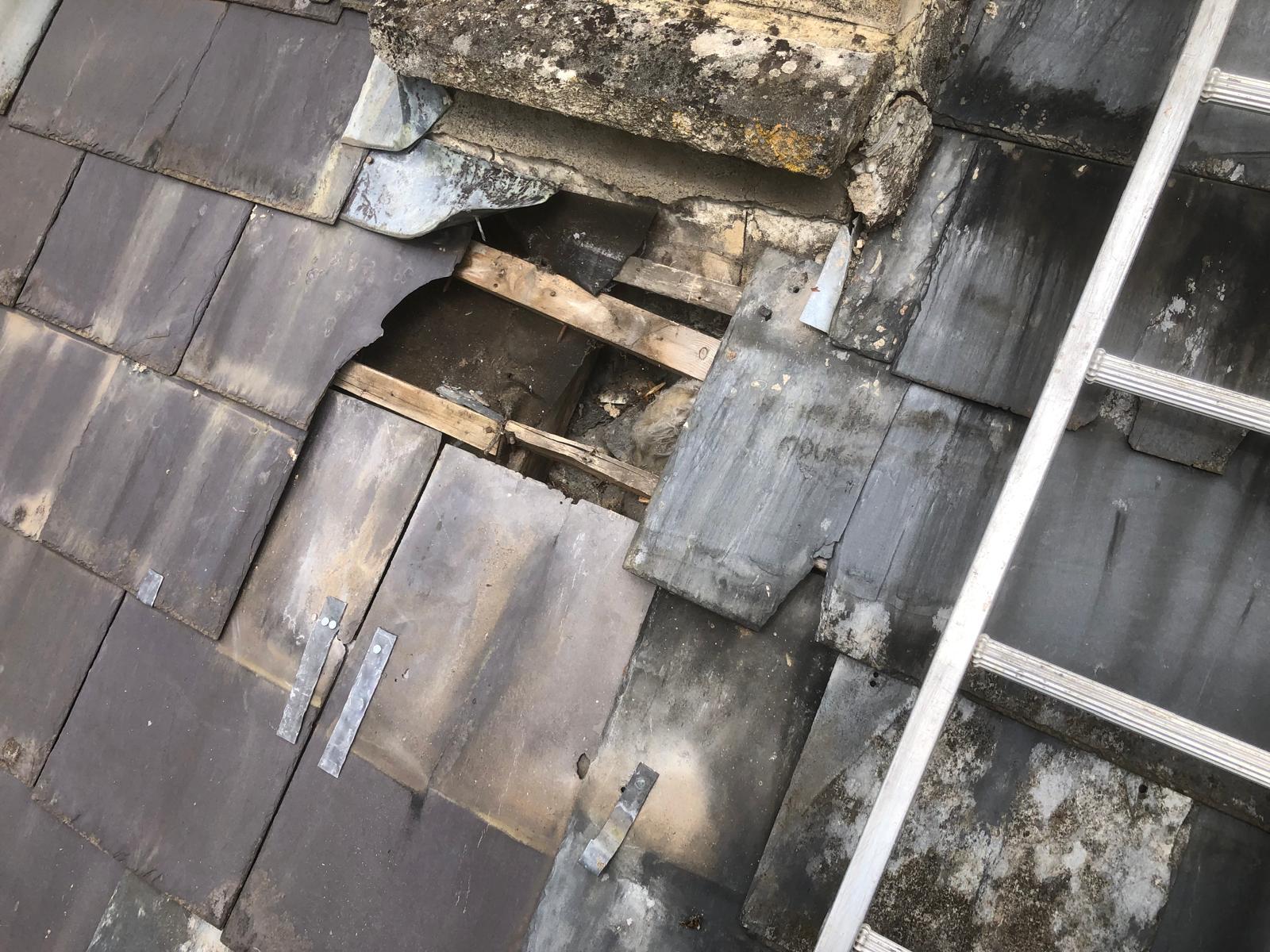 Roof opened beside a chimney to inspect failed battens, underlay and timber